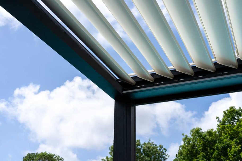 Trendy outdoor patio pergola. sky and clouds pass through the metallic structure. green trees in the background