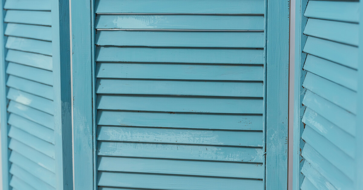 The texture of the battens of a blue wooden slats screen. Casement shutters